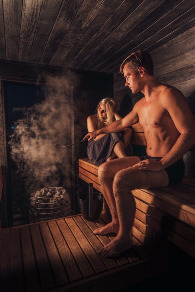 A couple enjoying a relaxing time in a warmly lit Nordic sauna.