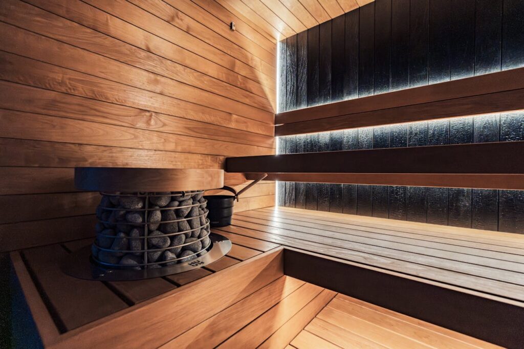 A stylish and modern indoor sauna with a premium heater and wooden panels, offers a relaxing wellness retreat.
