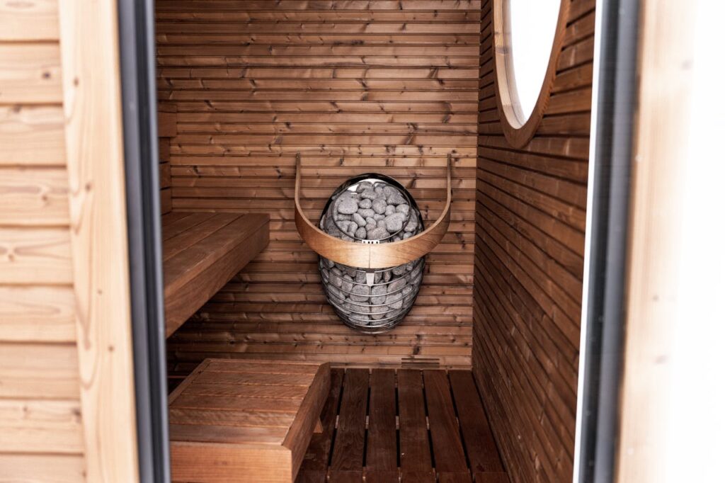 Explore the inviting wooden interior of a modern sauna with elegant design and a classic heater.