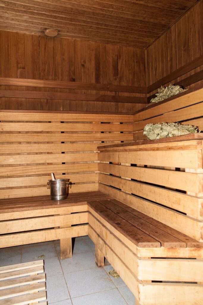 Warm wooden sauna room with benches and steam bucket for relaxation and rejuvenation.